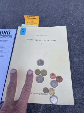Münzspenden auf Lehrbuch-Cover mit ausgelegtem vectoryz.org-Flyer